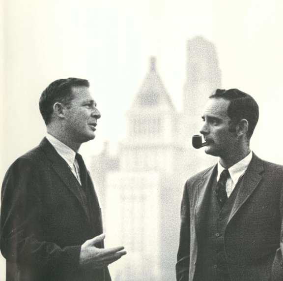 three men in suits standing in front of a city skyline