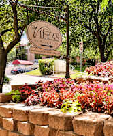 A sign that says "The Vineyards at Kate" is in front of a wall of red and green plants.