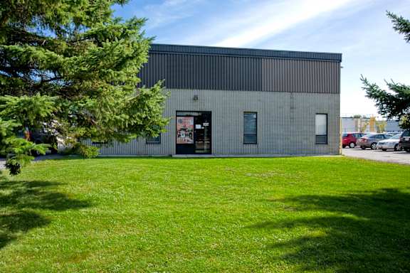 A building with a grey exterior and a green lawn in front.