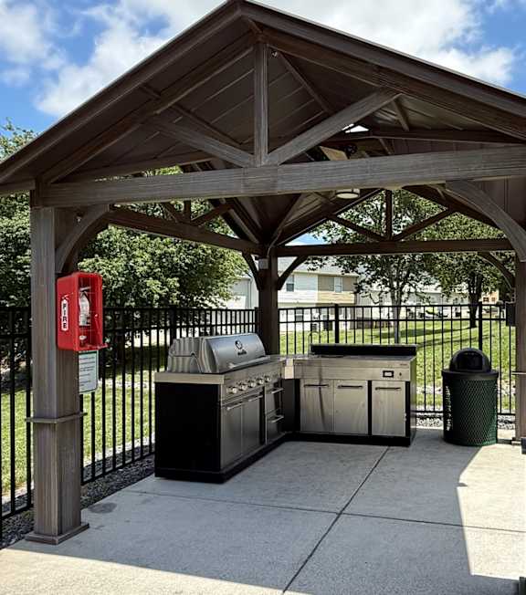A wooden pavilion with a trash can and recycling bin underneath it.