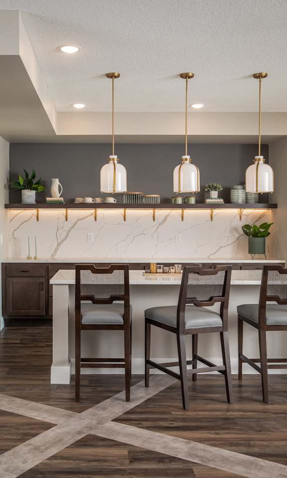 A kitchen with a marble countertop and wooden chairs.