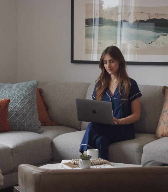 a woman sitting on a couch using a laptop computer