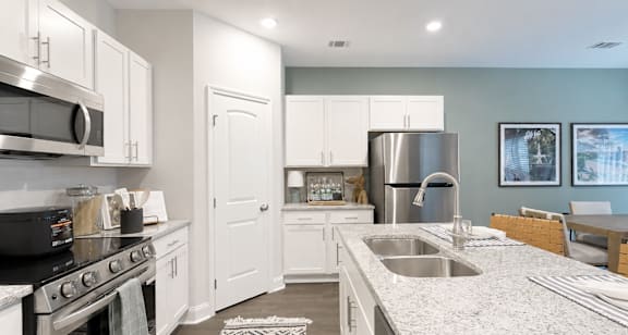 A kitchen with white cabinets and a stainless steel refrigerator.