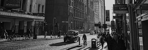 A black and white image of a row of houses with a street lamp in the foreground.