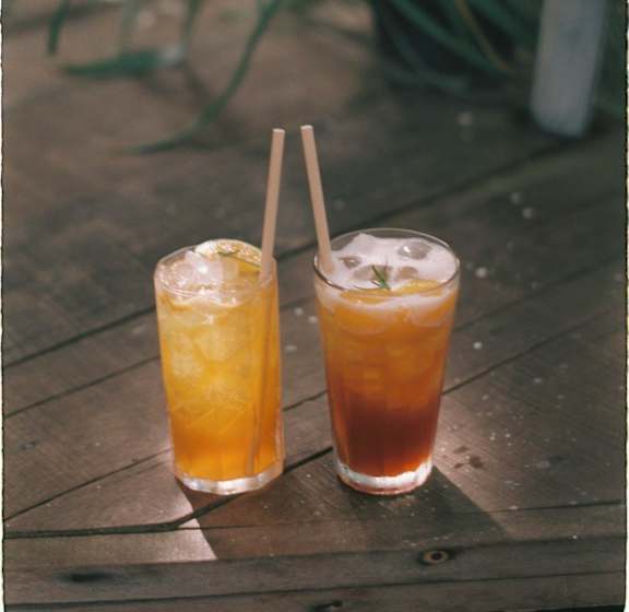Two glasses of iced tea on a wooden table.