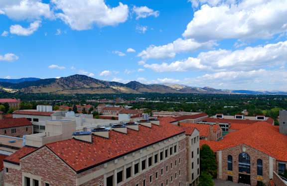A view of a town with buildings and mountains in the background.