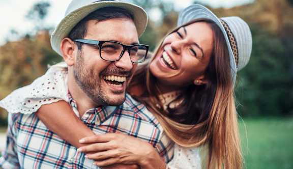 A man and a woman are laughing together in a field.