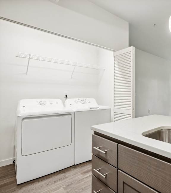 A modern kitchen with a white washing machine and a stainless steel sink.