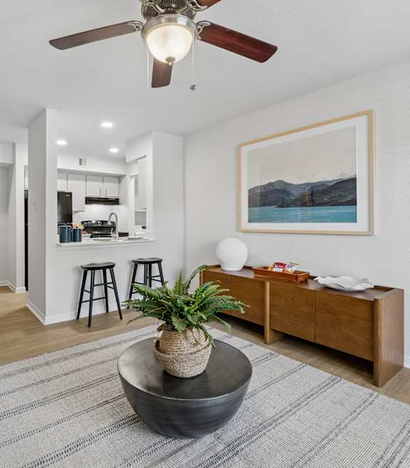 A living room with a ceiling fan, a rug, and a painting on the wall.