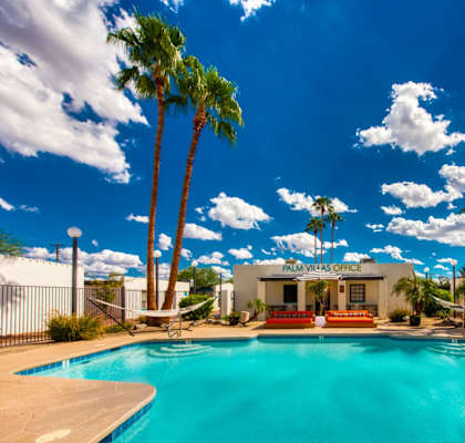 A pool surrounded by palm trees and a white building at Palm Villas, Scottsdale, 85257