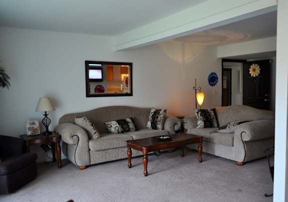 Living room in a Park 25 Apartments model unit, featuring a couch, a chair, and a table, offering a comfortable and inviting space.