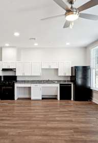 a white and black kitchen with a ceiling fan