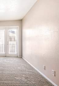 A room with a carpeted floor and a door leading to another room.