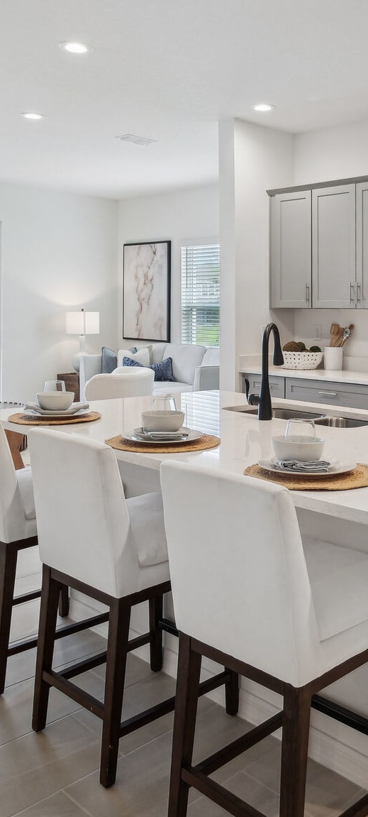 an open kitchen and dining area with a large island and white chairs