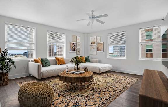 A living room with a white couch, a brown ottoman, and a rug.