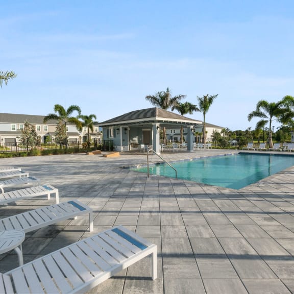 a swimming pool with white chairs and a building in the background