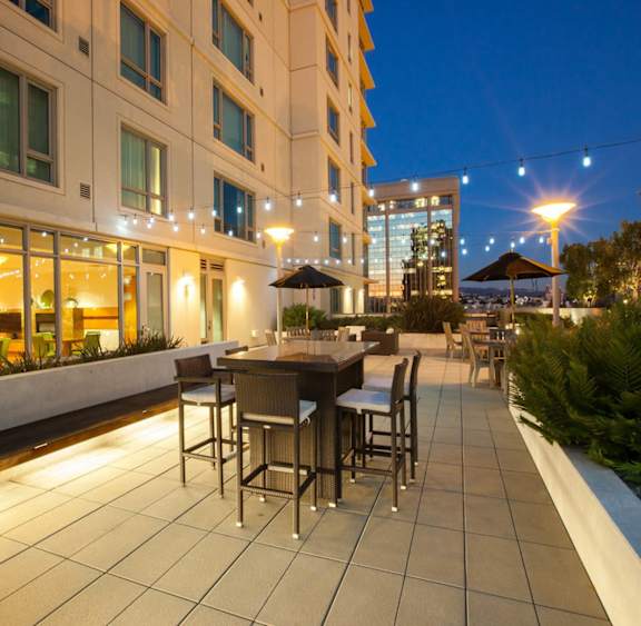 A patio with a table and chairs is lit up at night. at The Grand Apartments, Oakland, CA, 94612