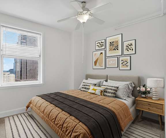 A bedroom with a bed, a ceiling fan, and pictures on the wall.