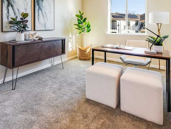 A room with a desk, chair, and two potted plants.
