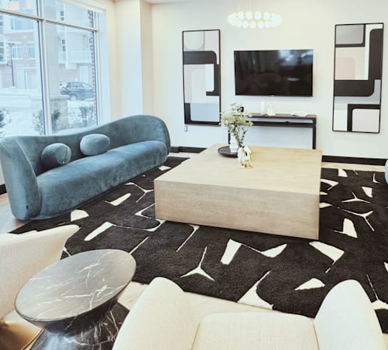 A living room with a blue couch, a wooden coffee table, and a black and white rug.