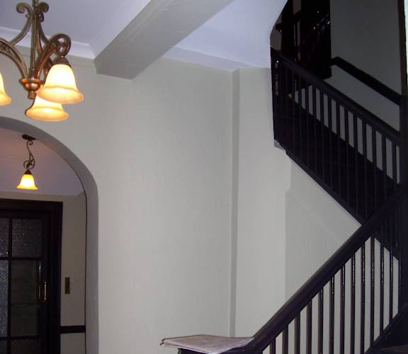 A staircase with a black railing and a white wall.