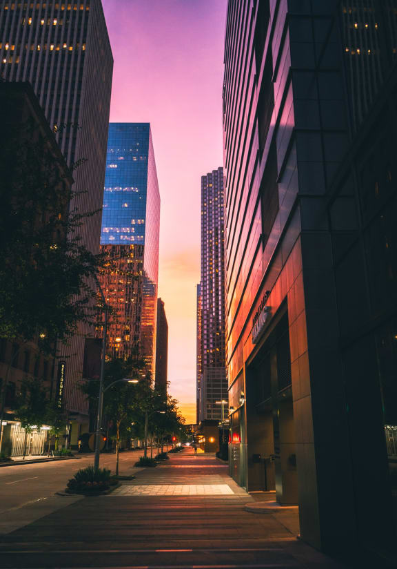 a city street with tall buildings at sunset
