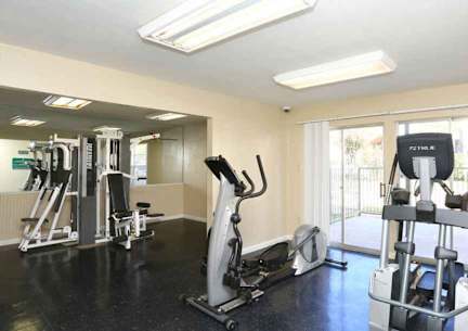 A gym with a variety of equipment including treadmills, weights, and exercise machines.