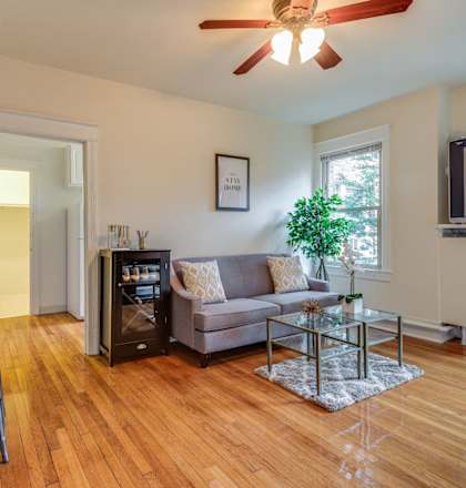 A living room with a grey couch and a wooden floor.
