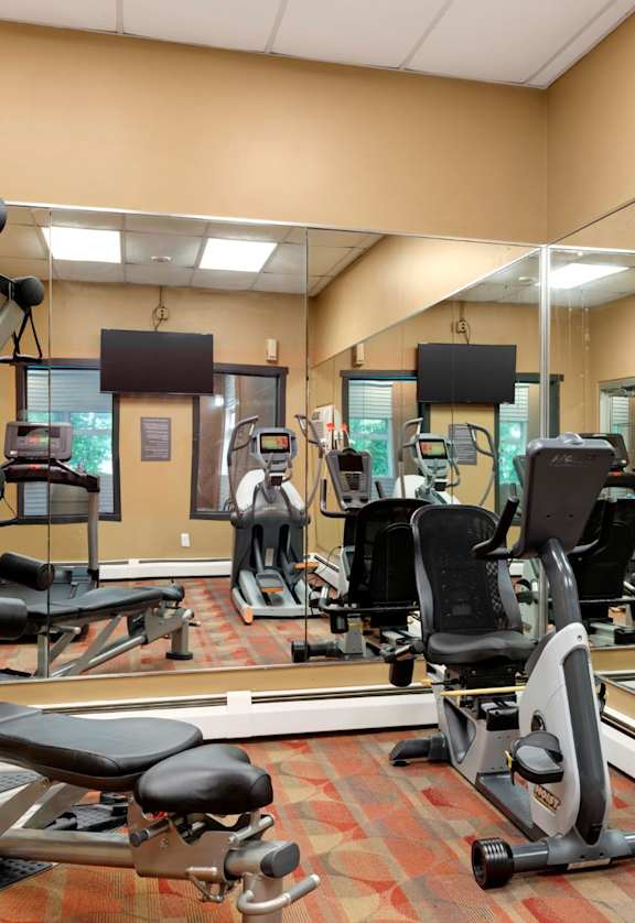 a gym with weights and cardio equipment in a room with mirrors at Hamline Terrace, Minnesota
