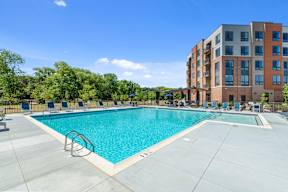 An L-shaped resort-style swimming pool with a sun deck, grills, lounge chairs, fire pits, and games at New Kent's Exton, PA apartment building. at Keva Flats, Exton, Pennsylvania