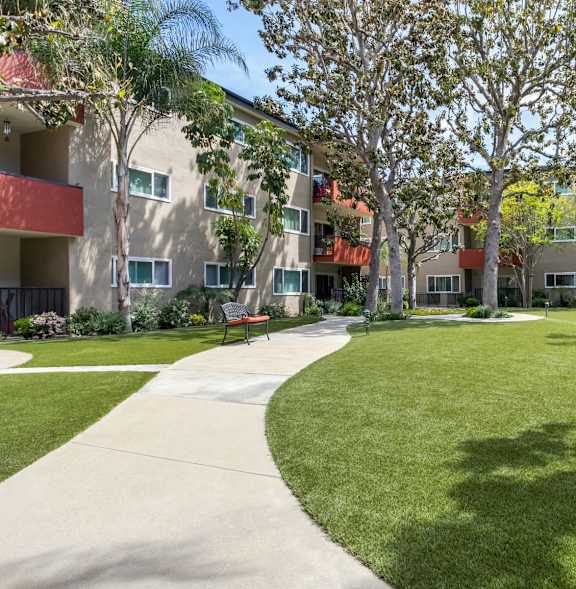 A sunny day at a grassy courtyard surrounded by apartment buildings. at White Oak Terrace Apartments, California