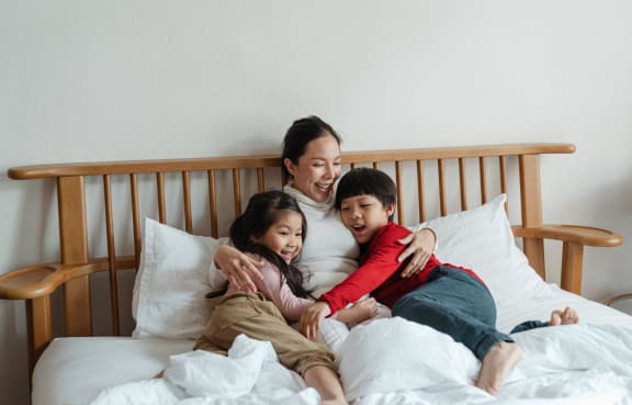 a mother and her two children laying on a bed at The Edge of Germantown, Memphis, TN