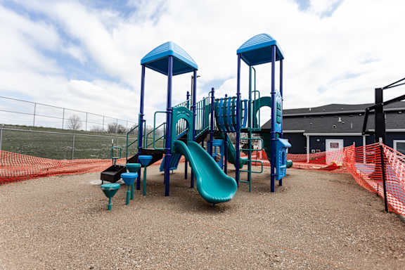A playground with a blue slide and a green slide.