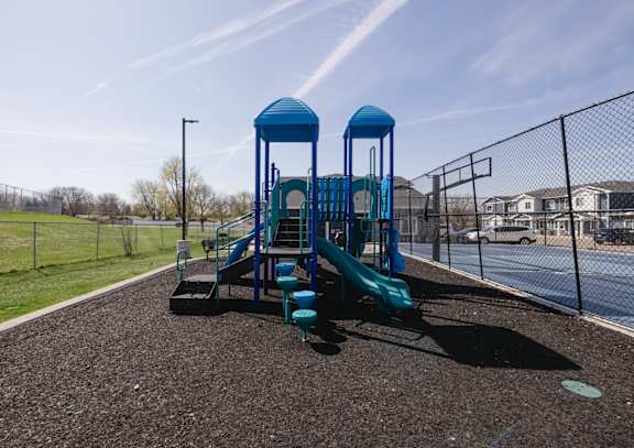A playground with a blue slide and two blue towers.