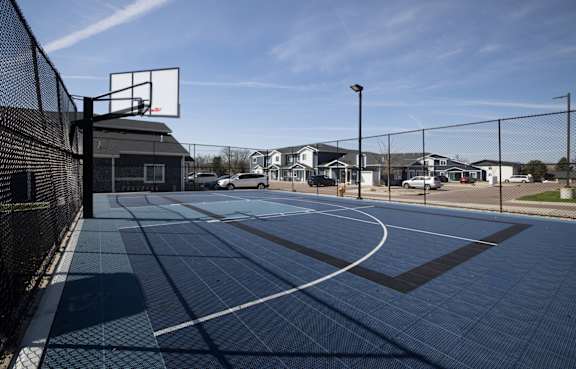 A basketball court with a black fence and a basketball hoop.