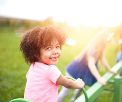 A child in a pink shirt is playing on a green playground equipment at Countryside River Apartments, Wilmington, IL