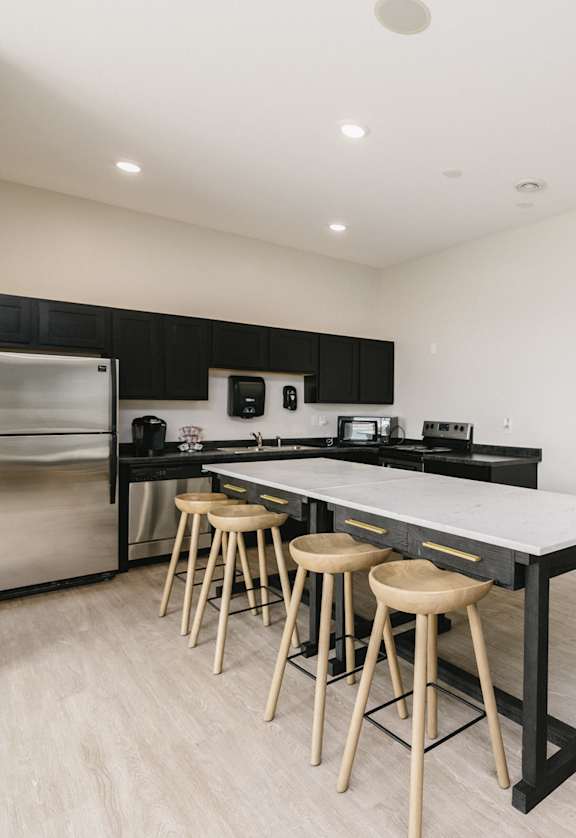 A modern kitchen with a large island and stools.