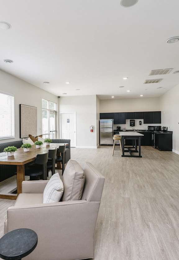 A modern living room with a large sofa, a dining table, and a kitchen in the background.