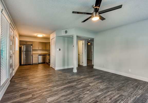 A room with a ceiling fan and wooden flooring.