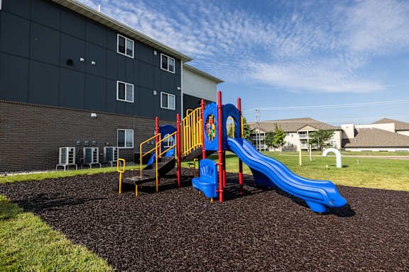 A playground with a blue slide and a red and yellow play structure.
