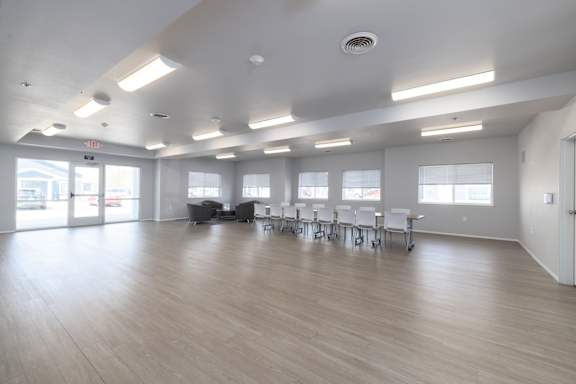 A large room with tables and chairs and a door.