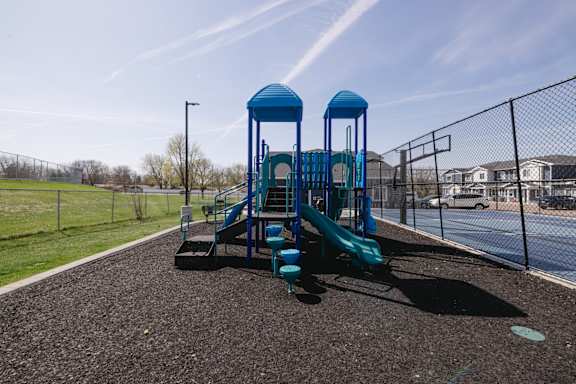 A playground with a blue slide and two blue towers.