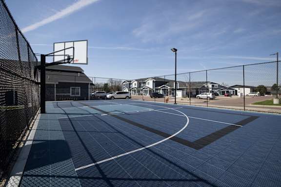 A basketball court with a black fence and a basketball hoop.