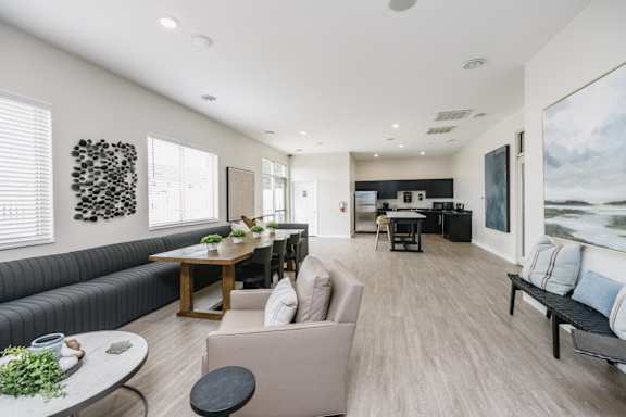 A modern living room with a large sofa, a dining table, and a kitchen in the background.