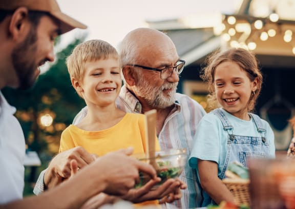 a man and two children talking to a family at a picnic table