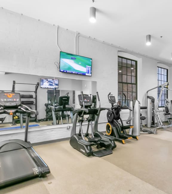 a gym with treadmills and other exercise equipment and a tv at Clocktower and Velvet Mill Apartments, Manchester, 06040