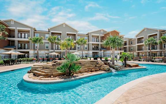 a swimming pool with palm trees in front of an apartment building