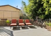 Thumbnail 33 of 41 - Apartments in Mar Vista CA - Vista - Outdoor Courtyard with Orange Cushioned Lounge Chairs, with Bike Rack, Trees, and Potted Plants