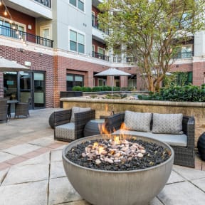 an outdoor patio with a fire pit and chairs