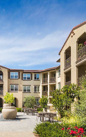 A large brown building with a pool in front.